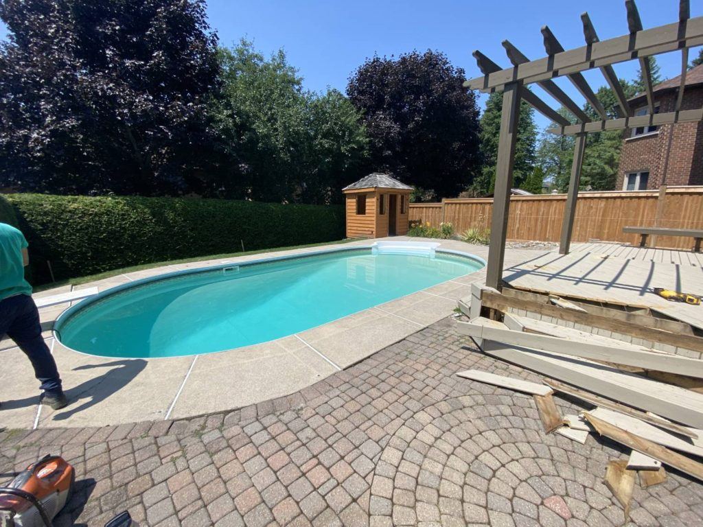 Swimming pool and backyard patio renovation project with pergola construction and landscaping work in progress