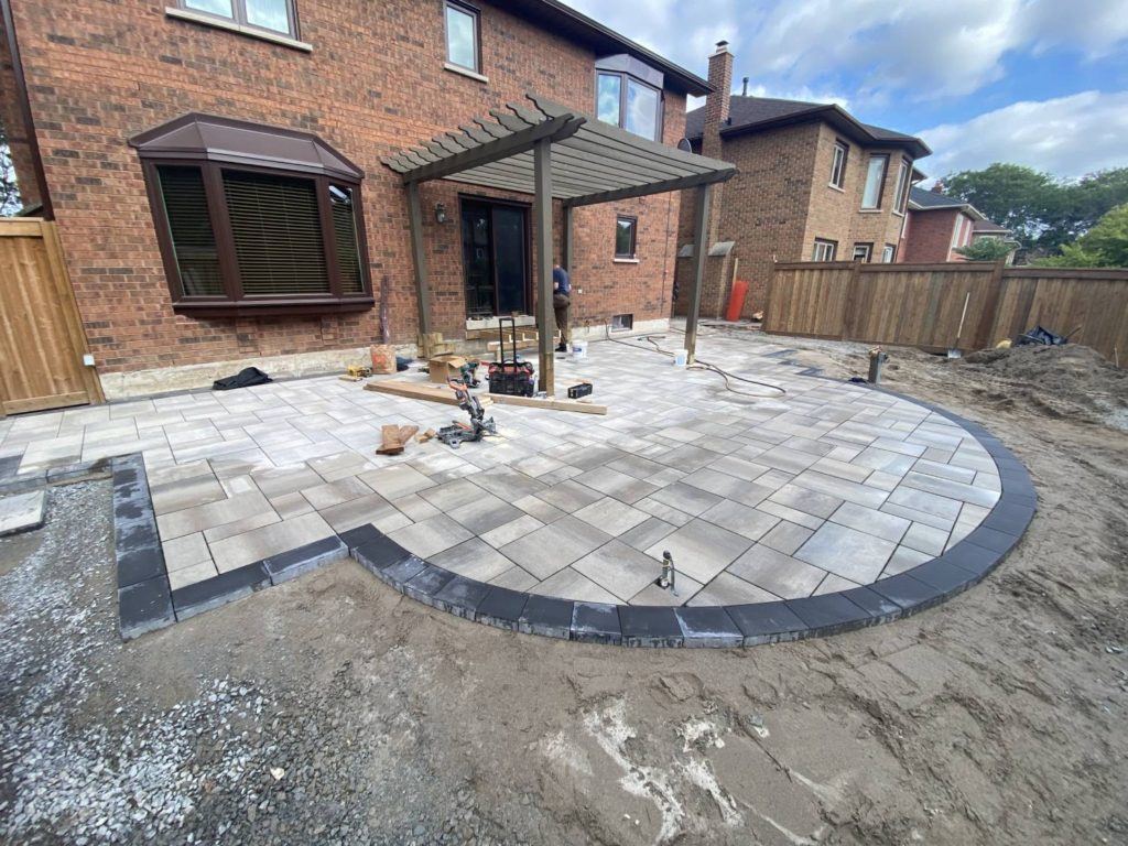 backyard patio installation with pergola and interlocking stone landscaping after pool removal project