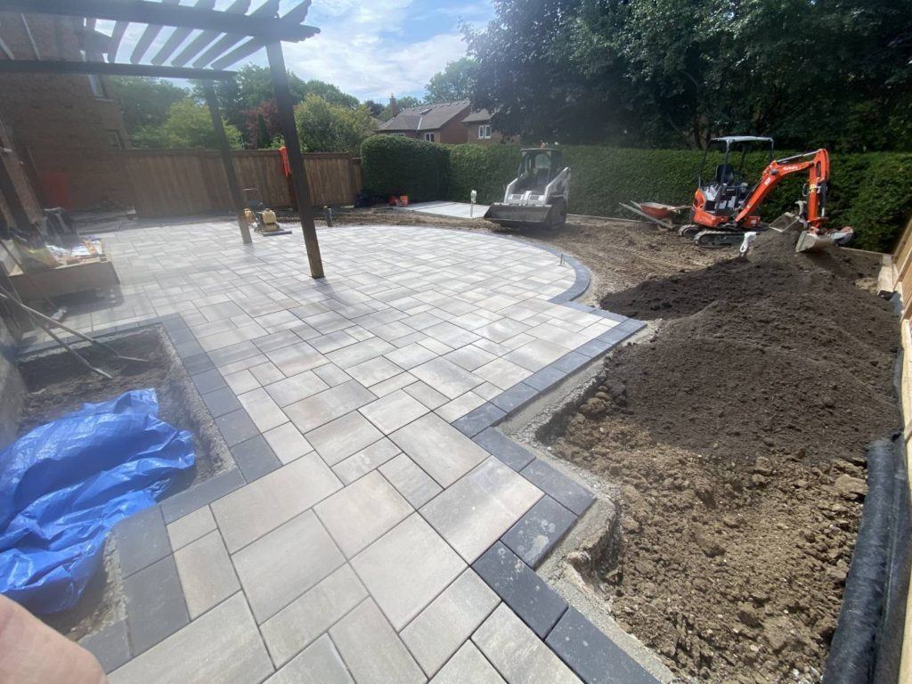 sand being placed and levelled around a patio