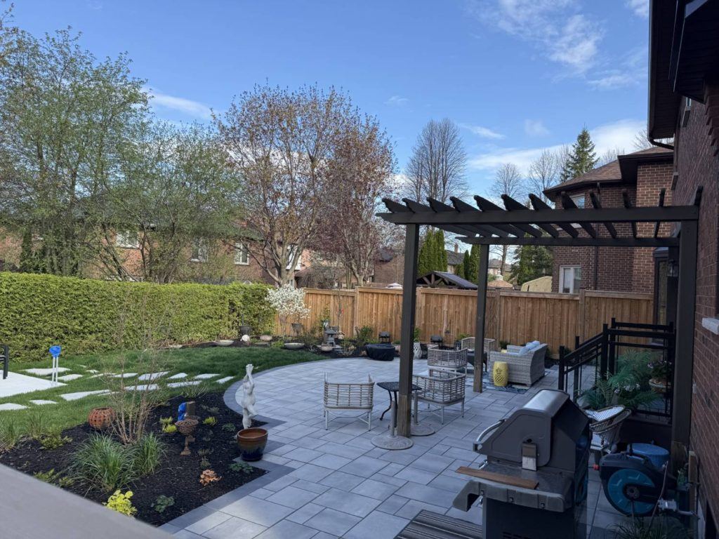 Landscaped backyard patio with pergola, outdoor seating, and garden beds after pool removal project