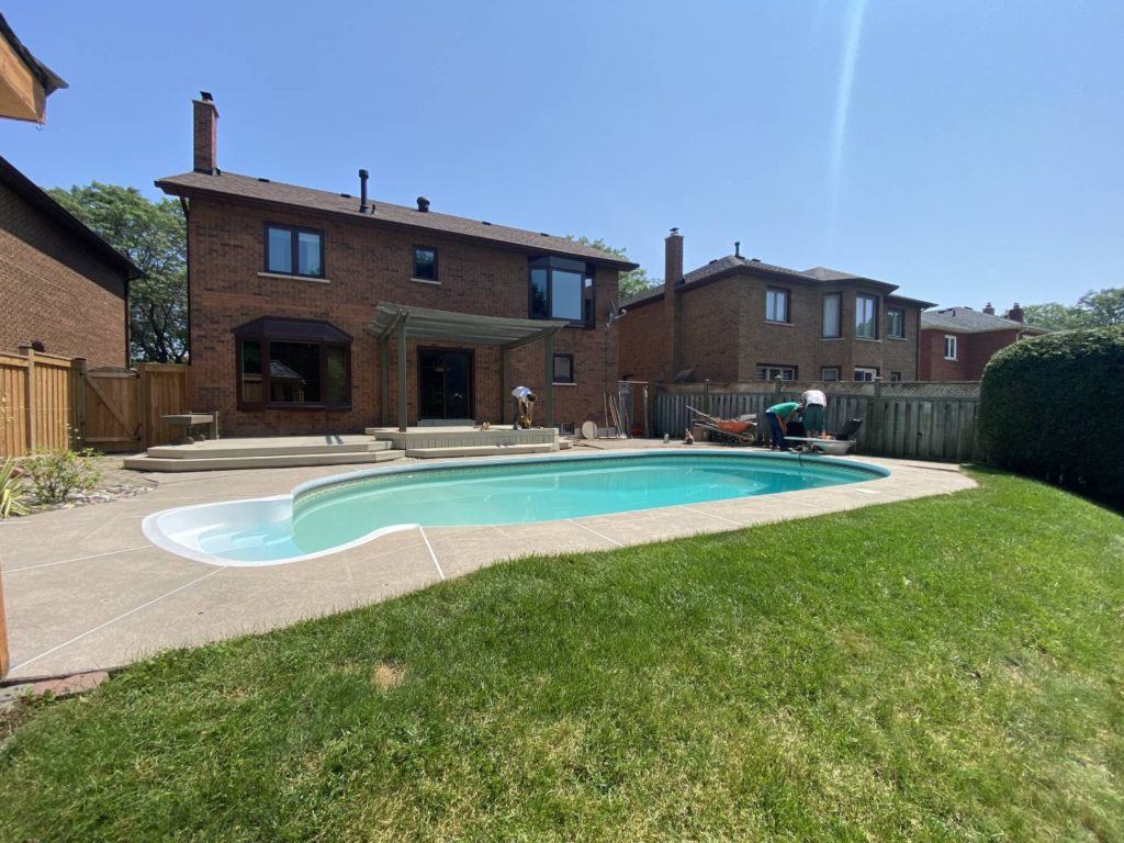 Finished backyard landscaping project with restored lawn, patio, pergola, and swimming pool at residential property