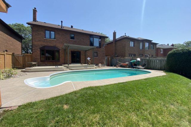 Finished backyard landscaping project with restored lawn, patio, pergola, and swimming pool at residential property