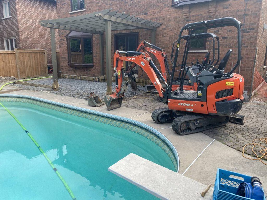 Kubota mini excavators beside residential swimming pool during backyard pool removal and landscaping project