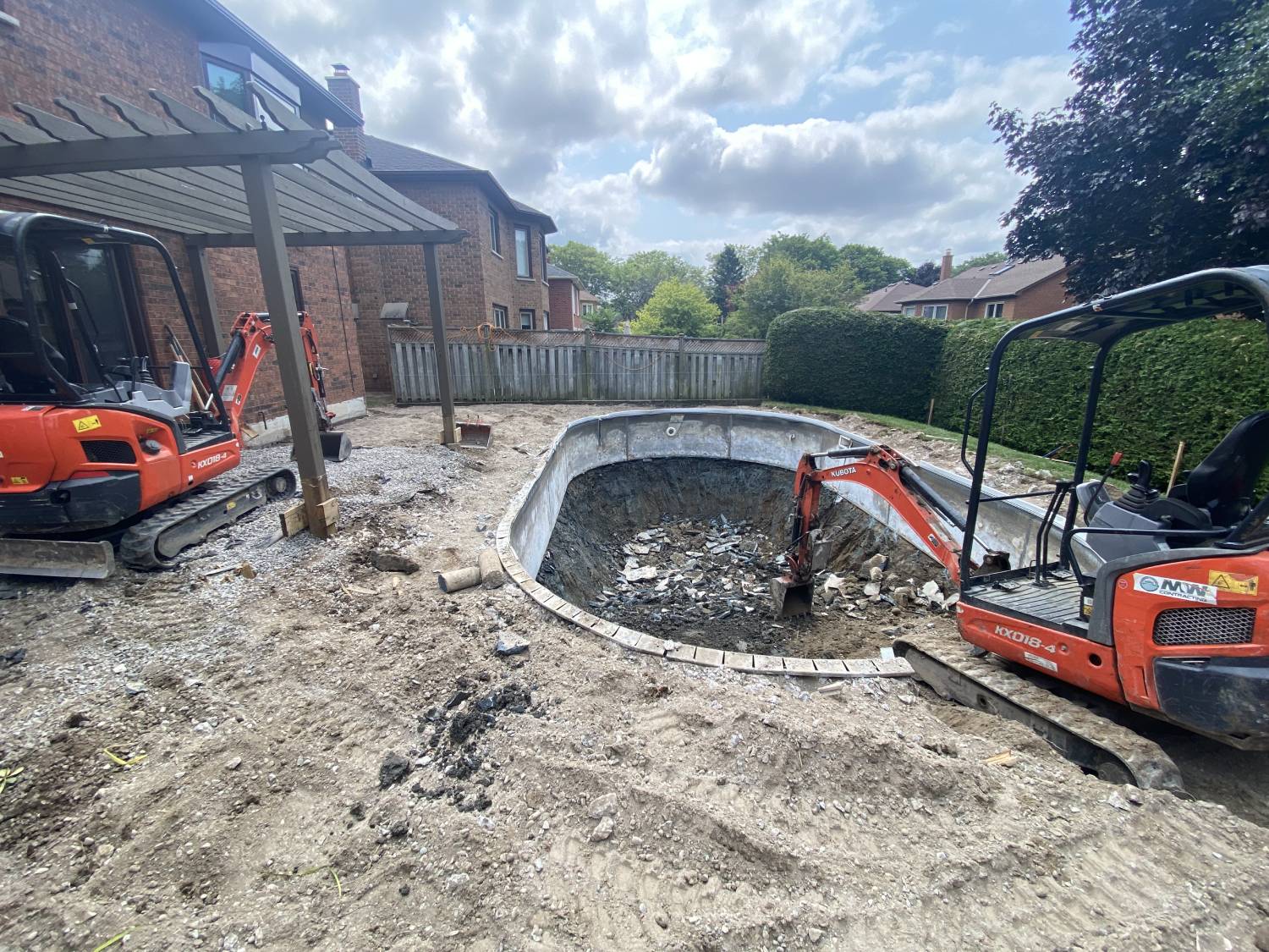 an excavator in the process of dismantling a concrete swimming pool
