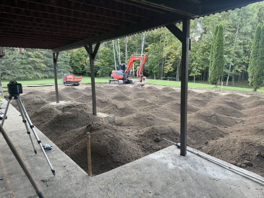 mini track dumper spreading topsoil during backyard restoration after pool removal project