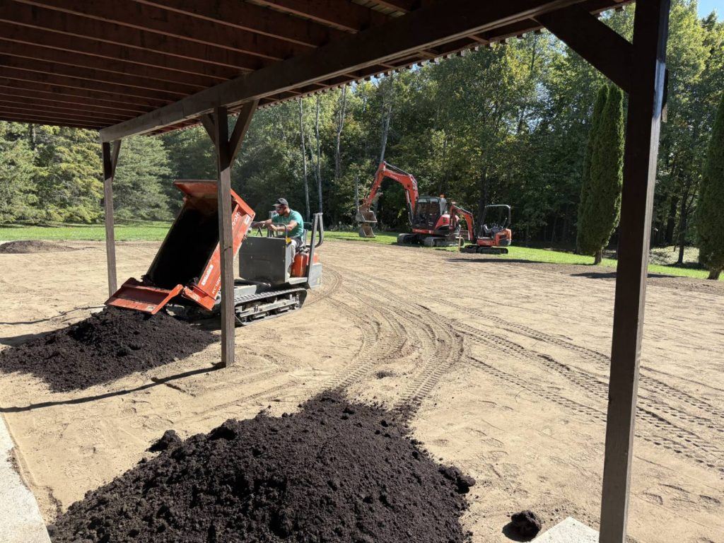 mini track dumper spreading topsoil during backyard restoration after pool removal project