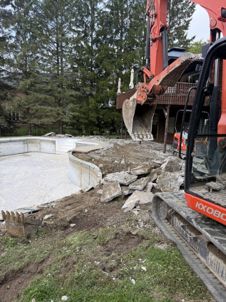an excavator in the process of demolishing a pool