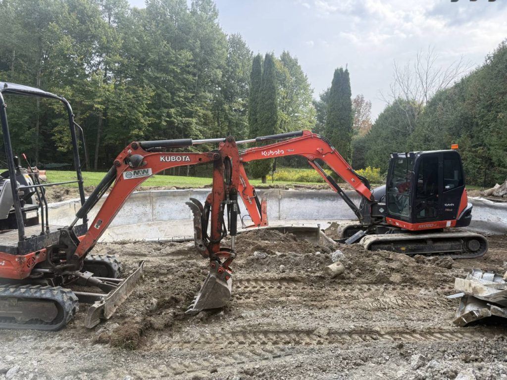 two excavators in the process of demolishing a pool