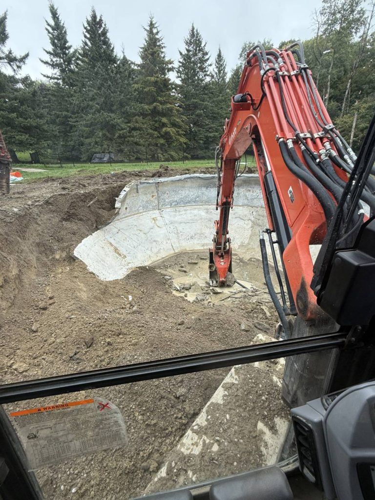 an excavator in the process of demolishing a pool