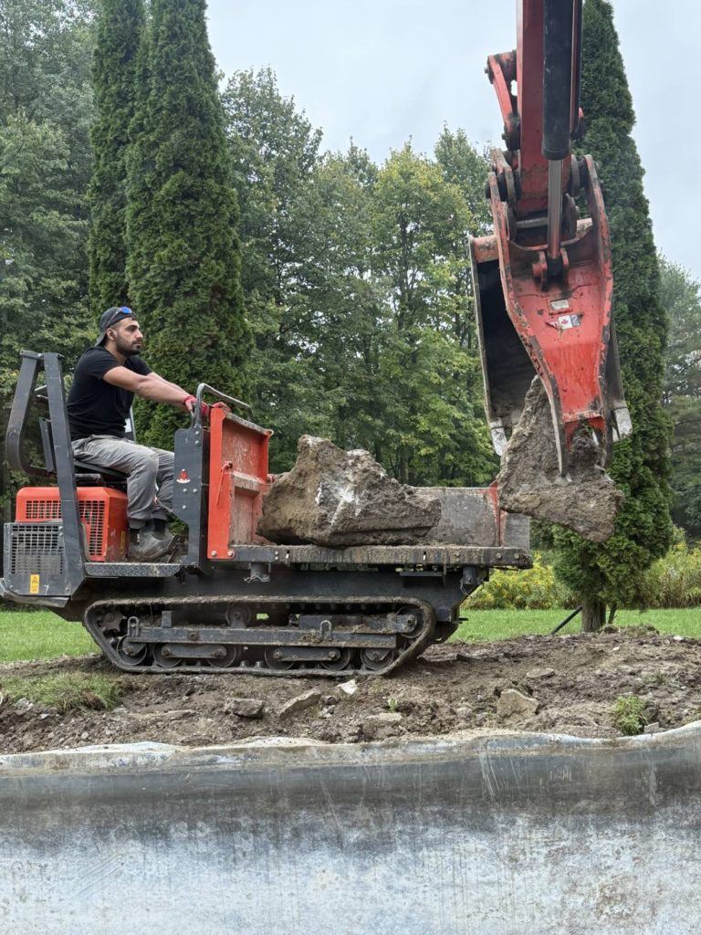 an excavator loading rocks on to a mini truck