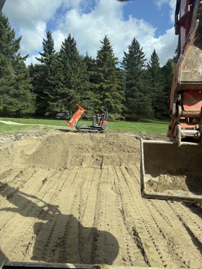 an excavator levelling sand after a pool removal