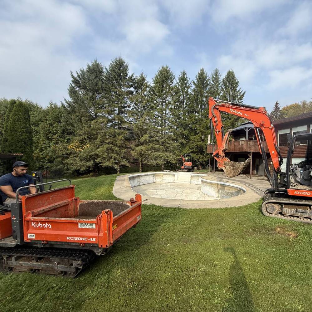 a digger starting to break up an empty pool