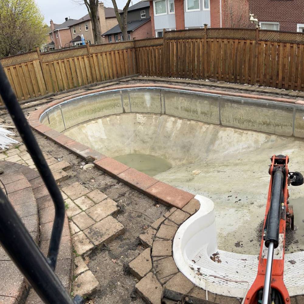 a digger starting to break up an empty pool