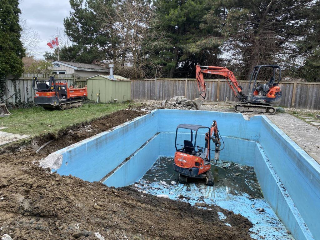 a kubota equipped with a jack-hammer breaking up a swimming pool