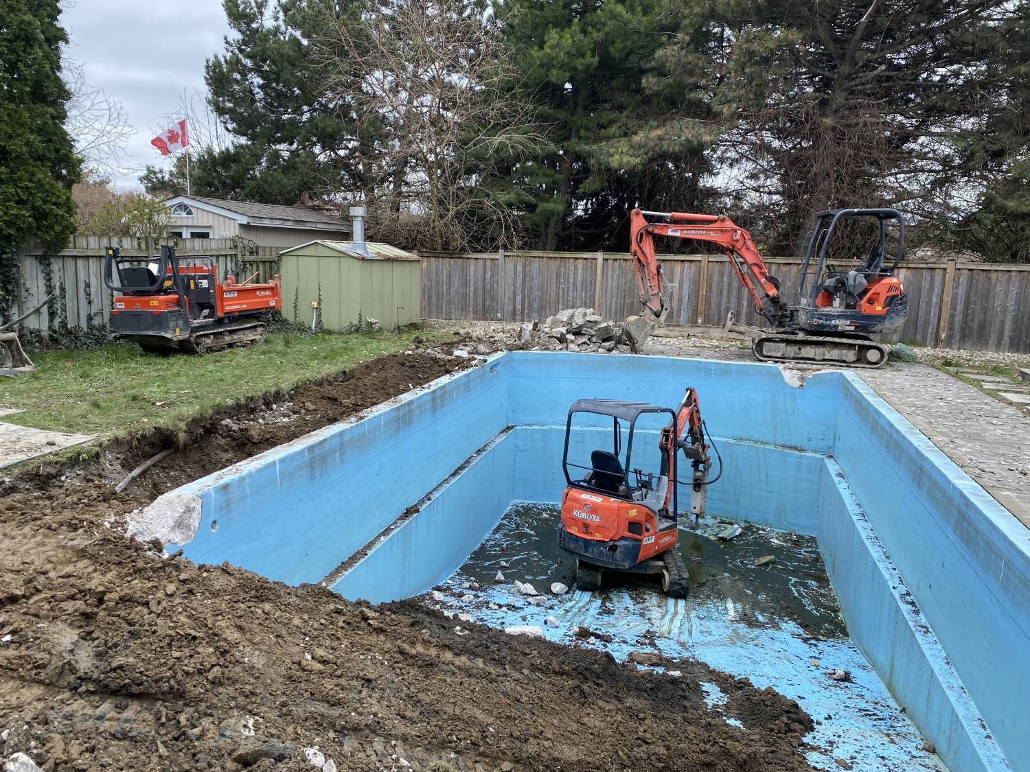 a kubota equipped with a jack-hammer breaking up a swimming pool