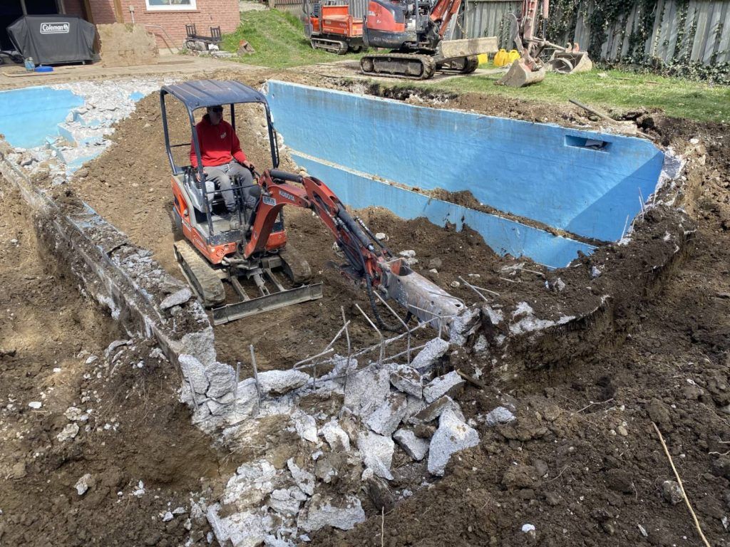 a kubota equipped with a jack-hammer breaking up a swimming pool