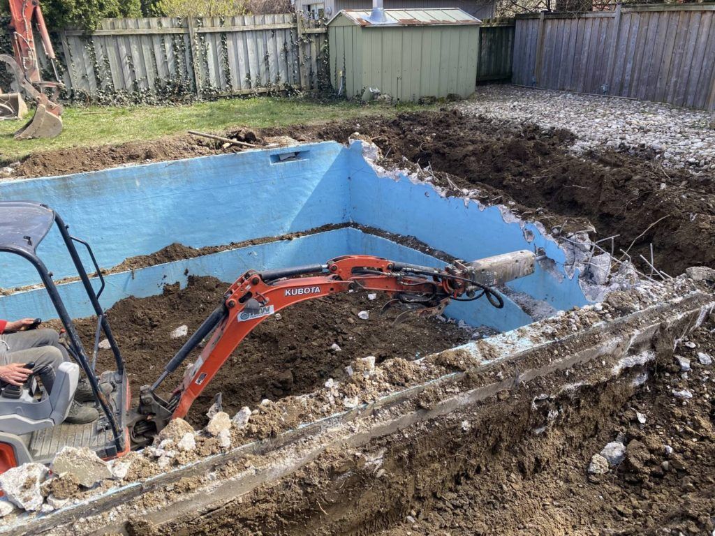 a kubota equipped with a jack-hammer breaking up a swimming pool