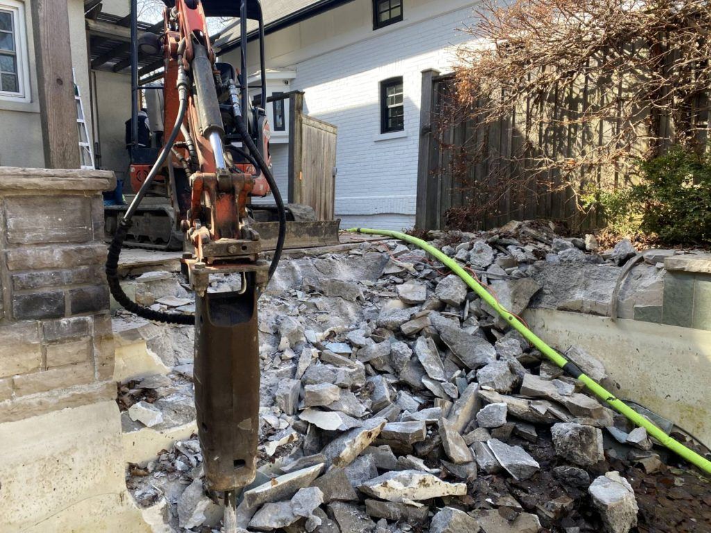 a kubota equipped with a jack-hammer breaking up a swimming pool