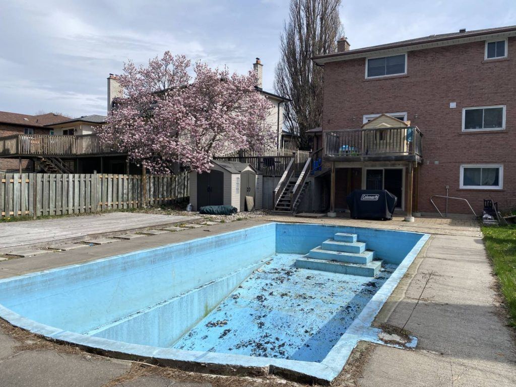 an empty swimming pool in a back garden