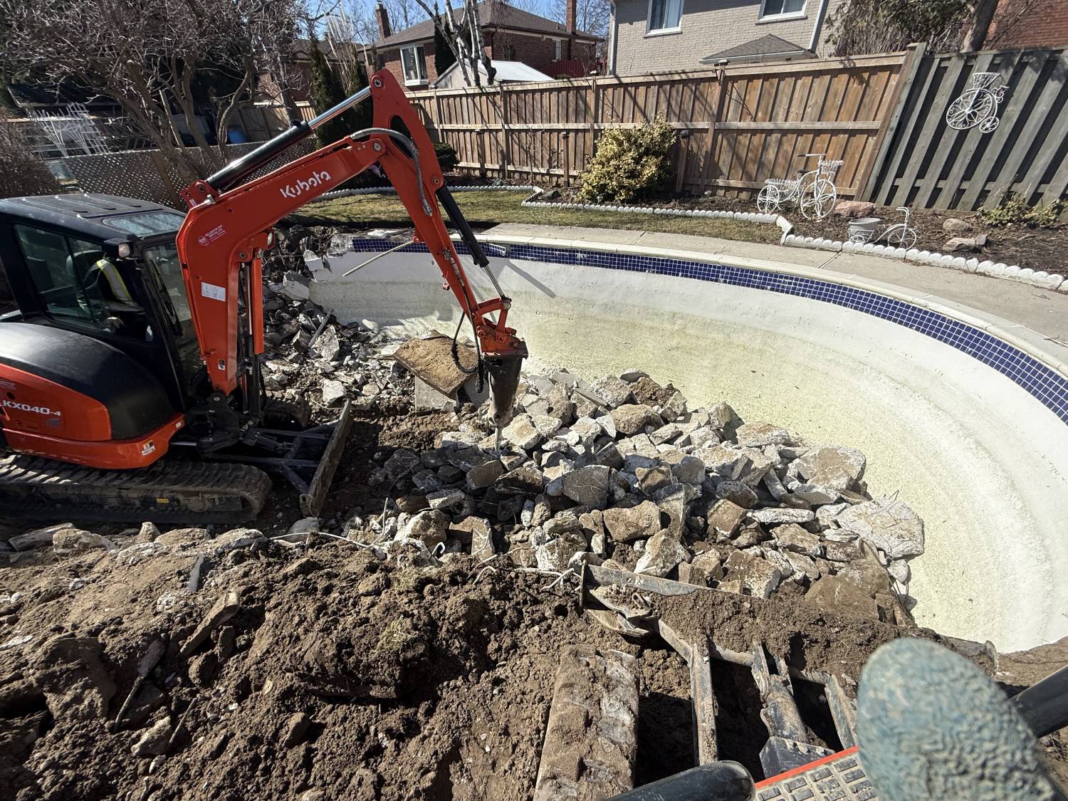 a kubota equipped with a jack-hammer breaking up a swimming pool